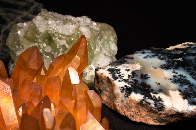 Orange, green, and variegated minerals on a black background