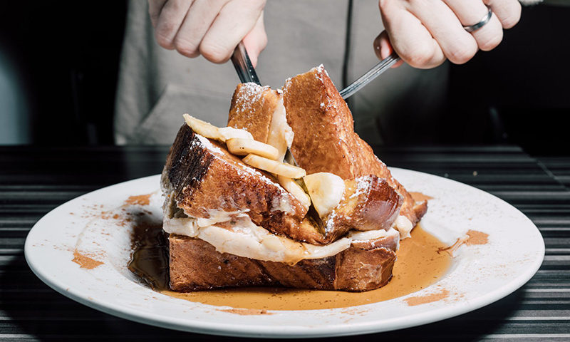 Challah french toast being cut by fork and knife