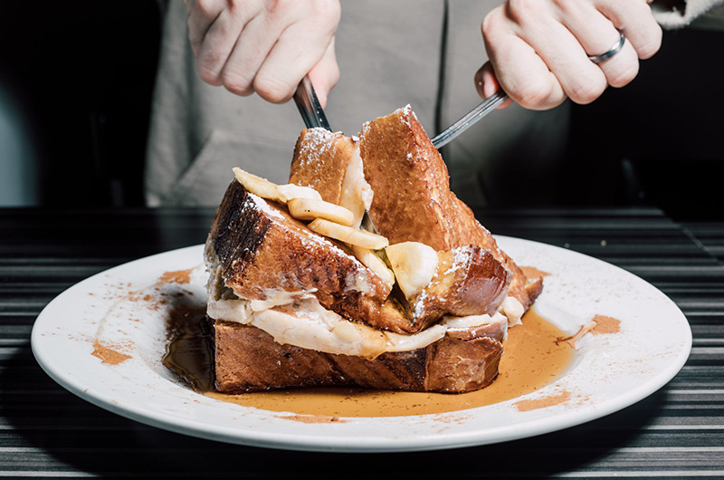 Challah french toast being cut by fork and knife