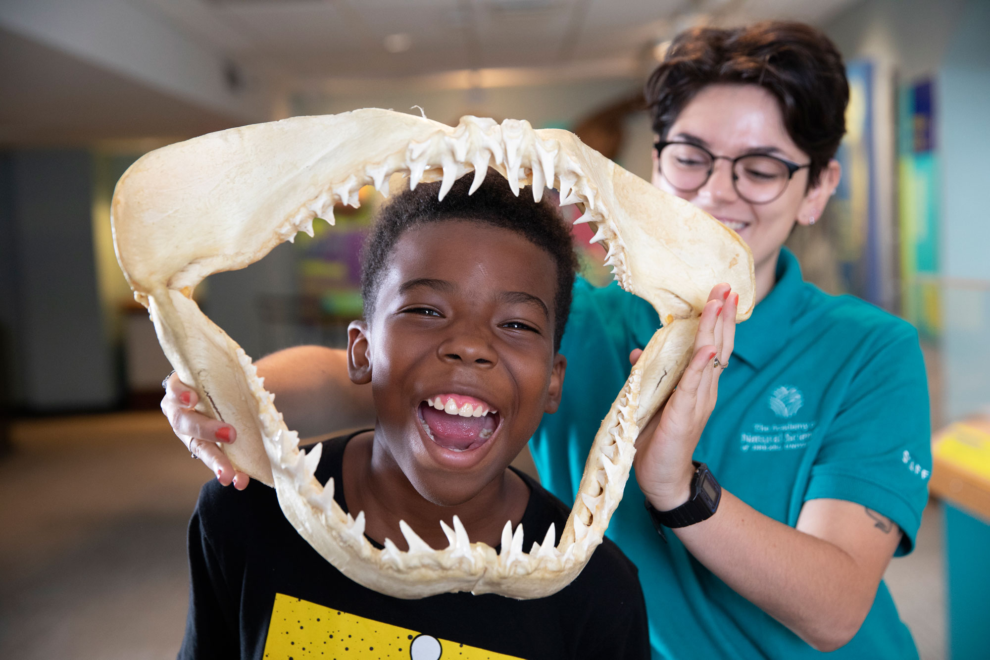Educator holds large animal jaw around child's face