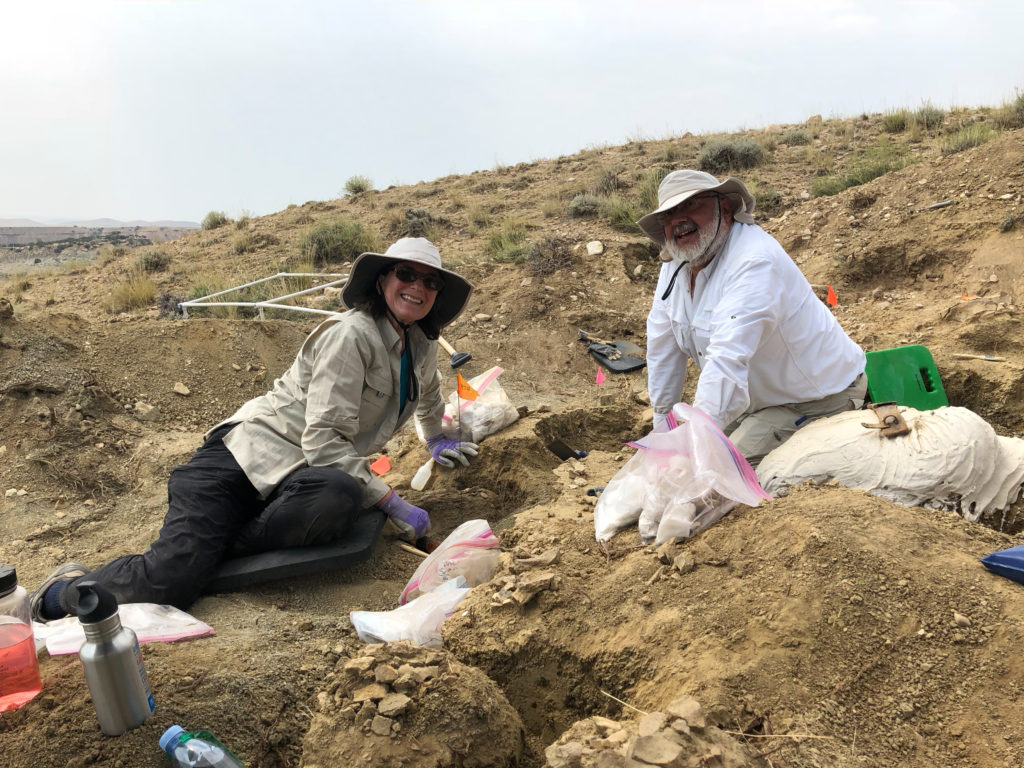 Karen and Wayne Lattuca digging in the dirt in Montana, wearing sun hats and surrounded by tools of the trade