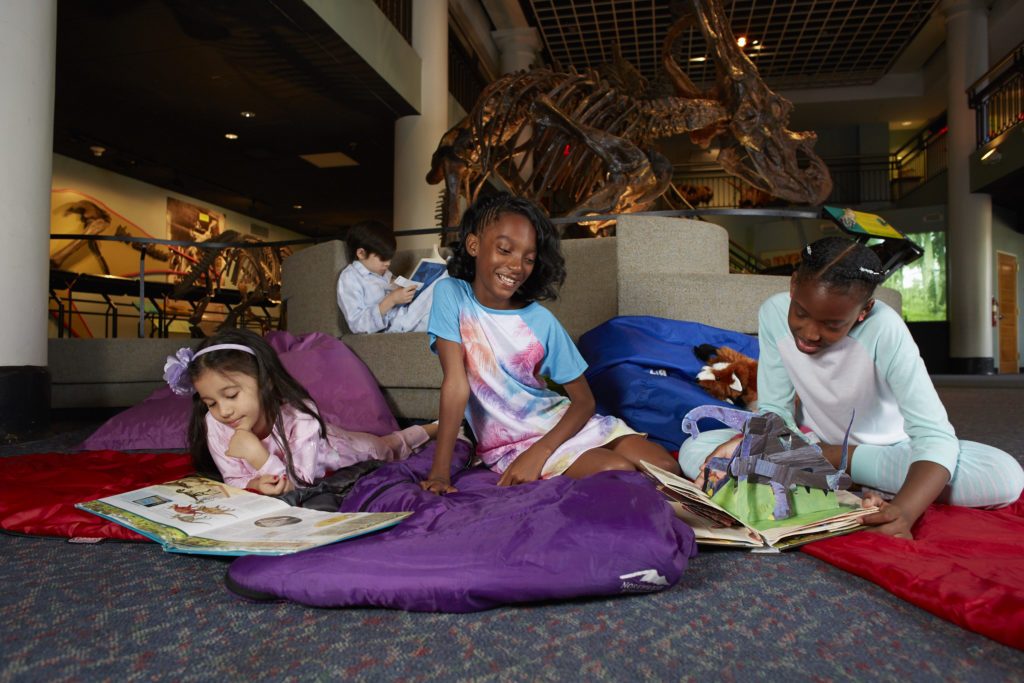 girls in sleeping bags under the T. rex