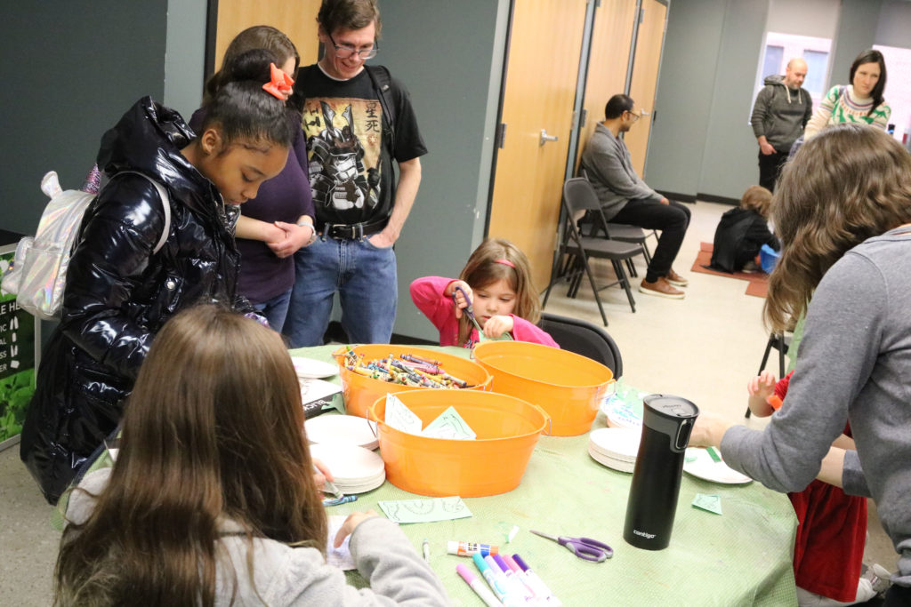 Children and adults make marine reptile crafts at small table