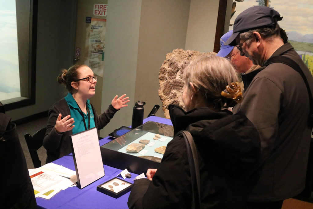 Female scientist exhibits trilobite fossils for three adults
