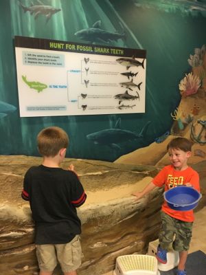 Two young visitors play in the sand box trench in Outside In!
