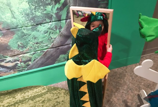 A child plays dress up as part of the interactive Mythic Creatures Exhibit.