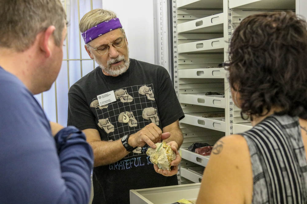 Man with headband shows minerals to couple
