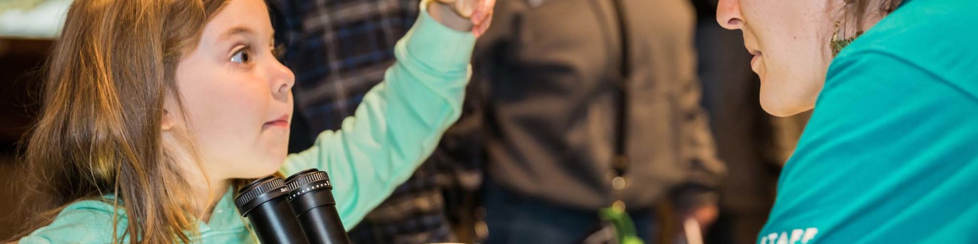 Little girl looks at female scientist, wide eyed