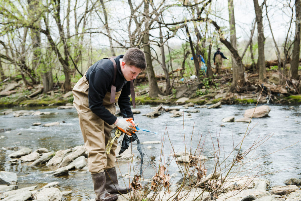 Young man picks up trash in Frankford Creek