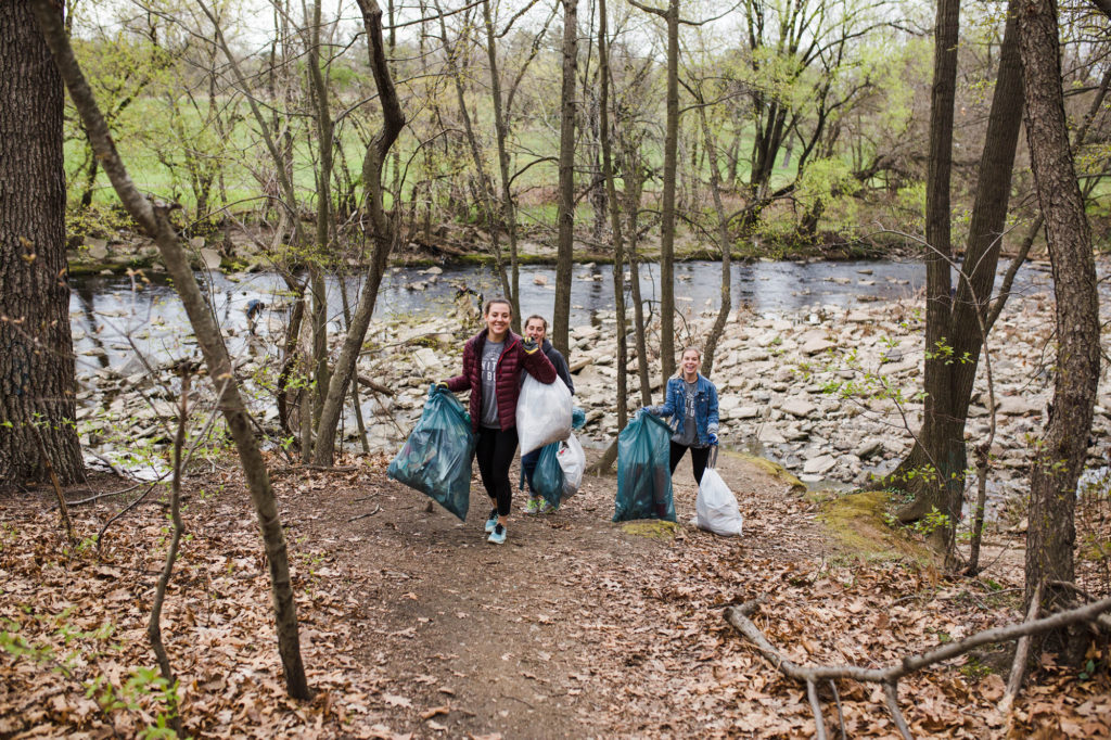 Young adults carry bags of trash from Frankford Creek