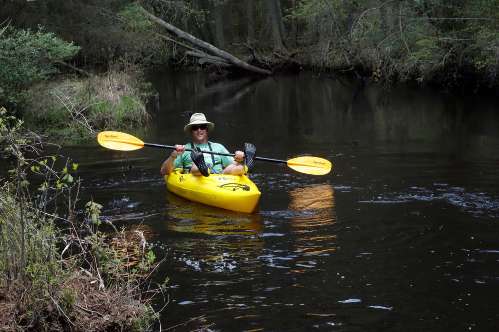 Man in sun hat paddles yellow kayak