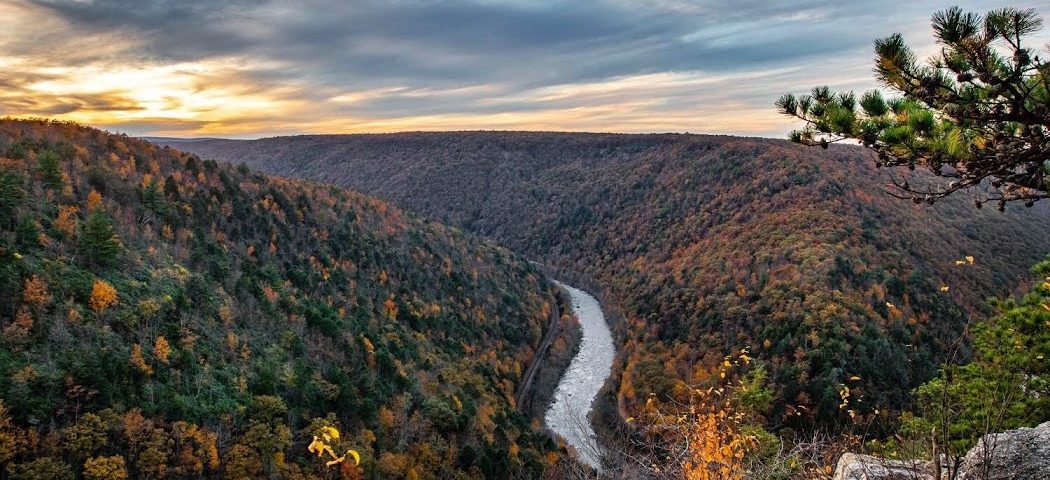 vista looking over river with red and orange fall foliage